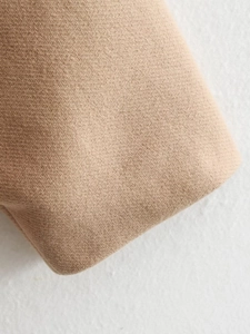 Macro view of khaki wool fabric texture and twill weaving on a minimalist women's overcoat