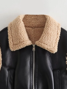 Détail de la veste en cuir noir avec col en peau de mouton beige et fermeture éclair argentée