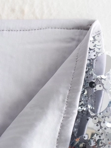 Detailansicht der silbernen Pailletten und des grauen Innenfutters eines Minirocks