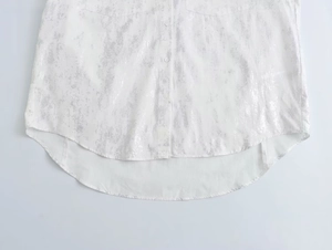 Detail view of white shirt featuring silver marble pattern and curved asymmetric hemline