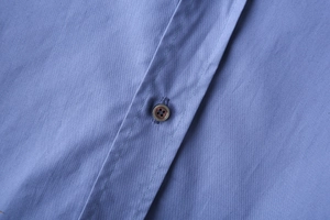 Vue macro d'une chemise en popeline à rayures montrant le bouton et les détails de couture