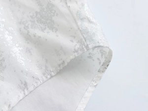 Close-up of white shirt with silver metallic foil print and neat stitching detail
