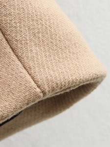 Detail shot of the beige woven fabric texture and seam stitching of the winter coat