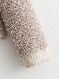 Close-up of soft teddy fleece fabric texture and ribbed knit cuffs in beige