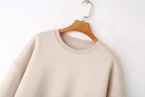 Close-up of ribbed crew neck and drop shoulder detail on cream oversized sweatshirt