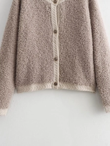 Detail of mauve bouclé knit cardigan with textured fabric and vintage metal buttons