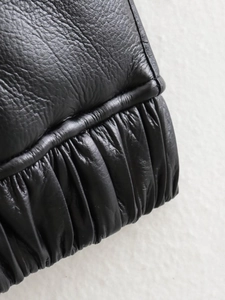 Detalle de chaleco de cuero negro con dobladillo elástico fruncido y textura granulada