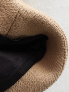 Close-up of camel wool texture with black lining on a casual Y2K loose autumn coat
