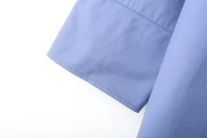 Vue détaillée du poignet de chemise en popeline rayée avec coutures nettes et tissu bleu clair