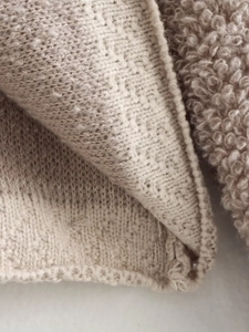 Close-up of beige knit cardigan fabric featuring jacquard FF pattern and fuzzy fleece lining