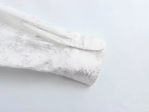 Detailed macro view of white shirt cuff with metallic print and single button closure