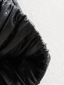 Détails de gilet en cuir noir avec texture plissée élégante et finition brillante chic