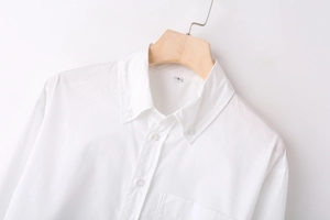 Detailed close-up of a white long-sleeved shirt with a button-down collar on a hanger