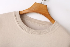 Close-up of ribbed crewneck and soft fleece texture on beige long sleeve sweatshirt