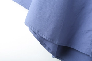 Vue détaillée de la chemise bleue Y2K montrant l'ourlet incurvé et les doubles coutures
