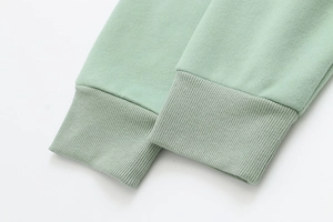 Close-up detail of the ribbed knit cuffs and soft cotton fabric on a mint green hoodie