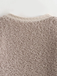 Macro shot of knit cardigan collar featuring textured bouclé yarn and ribbed neckline