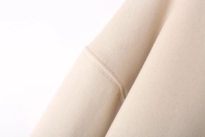 Macro detail of beige knit fabric showing precision double-needle stitching on sweatshirt