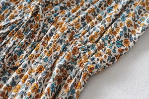 Detailed close-up of blue floral print ruffles and smocked elastic fabric on a summer dress