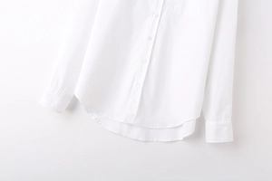Detail view of the white long sleeve shirt featuring chest pocket and curved hemline