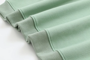 Close-up of mint green cotton hoodie featuring ribbed cuffs and high-quality knit texture