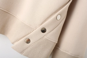 Detailed macro view of the almond knit sweater with silver snap buttons and ribbed hem