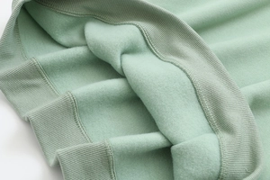 Macro detail of mint green hoodie featuring thick thermal fleece lining and ribbed cuffs