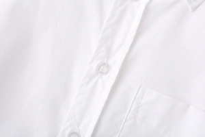 Detail of white long sleeve shirt featuring a square chest pocket and button closure