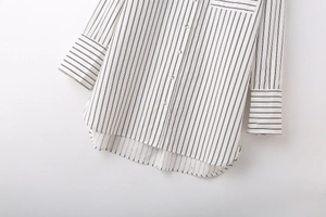 Detailed flat lay of a striped button-down shirt showing fabric texture and curved hem