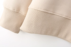 Macro detail of the ribbed knit cuff and smooth fabric of this beige Y2K style sweatshirt