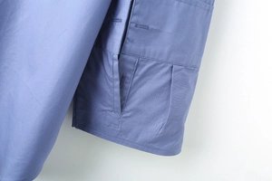 Détail du poignet d'une chemise en popeline rayée bleue avec coutures et boutonnière