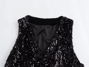 Detailed close-up of black sequin vest showing the V-neckline and shiny reflective texture