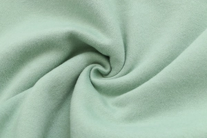 Macro view of light green cotton knit fabric texture with soft brushed fleece finish