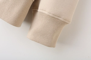 Detail shot of ribbed cuffs on a beige long-sleeved sweatshirt with neat stitching