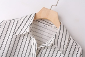 Detailed close-up of a Y2K style black and white striped shirt with a collar on a wooden hanger