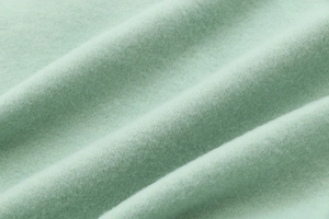 Close-up of soft mint green fleece fabric texture on a long hooded sweatshirt