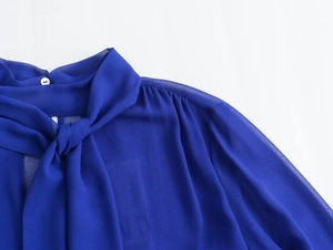 Detail of dark blue chiffon blouse showing the bow tie neckline and pleated shoulder seams