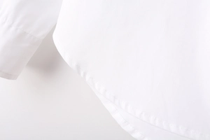 Detailed macro view of the curved hem and precise stitching on a white Y2K long-sleeve shirt