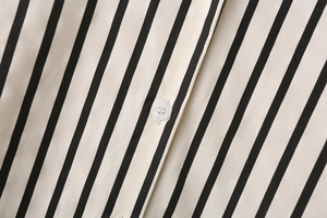 Close-up of black and white striped poplin fabric with a white four-hole button detail