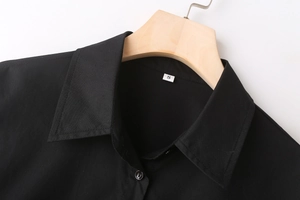 Detailed view of black poplin shirt collar with button placket and size S label