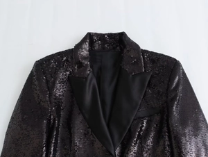 Detail of sequined short jacket with black satin lapel and shimmering party finish