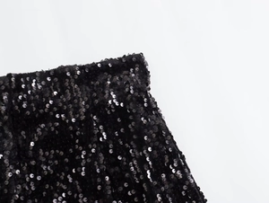 Dettaglio ravvicinato dei pantaloncini neri con paillettes a vita alta e trama lucida