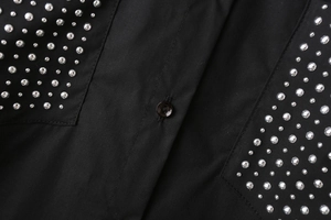 Detail of black poplin shirt with silver stud embellishments and black button closure
