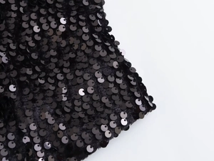 Macro shot of shimmering black sequins sewn on soft velvet fabric of a fitted vest