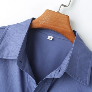 Close-up of blue striped poplin shirt collar with S size label on wooden hanger
