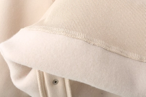 Detailed macro view of beige fleece lining and ribbed cuff with silver metal snap button
