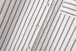 Detail of striped shirt showing vertical black stripes, white buttons, and neat stitching