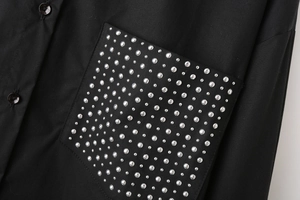 Detail of black poplin shirt featuring rectangular pocket with silver stud embellishments