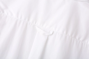 Detail view of the back yoke stitching and hanging loop on the white long sleeve shirt