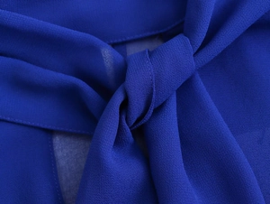 Detailed close-up of dark blue chiffon blouse featuring intricate bow tie neck design